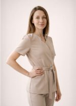 NOWA! TUNIKA MEDYCZNA – KOPERTOWA Nasza tunika przeszła prawdziwą metamorfozę – uwzględniliśmy wszystkie opinie naszych klientek, aby stworzyć model jeszcze lepszy i bardziej komfortowy w codziennej pracy. Nowa tunika nie rozchodzi się na biuście, dzięki czemu zapewnia pełną swobodę ruchów i komfort podczas pracy z pacjentem. Głębsze założenie na biuście sprawia, że nie ma potrzeby zakładania dodatkowego trykotu, a rezygnacja z mało estetycznych zatrzasków gwarantuje perfekcyjne ułożenie materiału. Wiązanie w talii pozwala dopasować tunikę do każdej sylwetki, podkreślając kobiece kształty i jednocześnie dbając o wygodę przez cały dzień. Pionowe cięcia wysmuklają sylwetkę, nadając całości eleganckiego charakteru. Dodatkowym atutem są trzy praktyczne kieszenie, w tym jedna zaprojektowana specjalnie na telefon. Poznaj i pokochaj naszą nową tunikę – stworzoną z myślą o Tobie!
