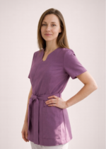NOWA! TUNIKA MEDYCZNA – KOPERTOWA Nasza tunika przeszła prawdziwą metamorfozę – uwzględniliśmy wszystkie opinie naszych klientek, aby stworzyć model jeszcze lepszy i bardziej komfortowy w codziennej pracy. Nowa tunika nie rozchodzi się na biuście, dzięki czemu zapewnia pełną swobodę ruchów i komfort podczas pracy z pacjentem. Głębsze założenie na biuście sprawia, że nie ma potrzeby zakładania dodatkowego trykotu, a rezygnacja z mało estetycznych zatrzasków gwarantuje perfekcyjne ułożenie materiału. Wiązanie w talii pozwala dopasować tunikę do każdej sylwetki, podkreślając kobiece kształty i jednocześnie dbając o wygodę przez cały dzień. Pionowe cięcia wysmuklają sylwetkę, nadając całości eleganckiego charakteru. Dodatkowym atutem są trzy praktyczne kieszenie, w tym jedna zaprojektowana specjalnie na telefon. Poznaj i pokochaj naszą nową tunikę – stworzoną z myślą o Tobie!